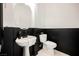 Stylish half bath features a pedestal sink, round mirror, and black and white color scheme at 8244 Cupertino Heights Way, Las Vegas, NV 89178