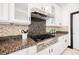 Close-up of a kitchen cooktop, granite countertops, and white cabinets, offering a gourmet cooking experience at 8244 Cupertino Heights Way, Las Vegas, NV 89178