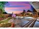 Charming outdoor living space with a stone patio, waterfall, fire pit, and gazebo perfect for entertaining guests under the vibrant sunset at 9180 Mohawk St, Las Vegas, NV 89139