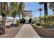 Community entrance with an arched entry, mature landscaping, stone wall, and palm trees at 10372 Timber Canyon Ave, Las Vegas, NV 89129