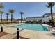 Community pool featuring clear blue water, landscaped areas, and shaded seating with palm trees at 10372 Timber Canyon Ave, Las Vegas, NV 89129