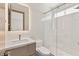 Modern bathroom featuring white tiled walls, glass shower, and sleek vanity with illuminated mirror at 11453 Glowing Sunset Ln, Las Vegas, NV 89135