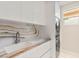 Modern laundry room with stacked washer and dryer, white cabinets, and stunning natural stone backsplash at 11453 Glowing Sunset Ln, Las Vegas, NV 89135