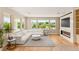 Living room with a white sofa, fireplace, large windows, and wood floors overlooking the green backyard at 11453 Glowing Sunset Ln, Las Vegas, NV 89135