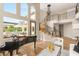 Open-concept living space with grand piano, access to outdoor patio, and a gracefully winding staircase at 11453 Glowing Sunset Ln, Las Vegas, NV 89135