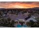 Aerial view of a luxury home, pool, mature landscaping, and mountain views at sunset at 1610 Brock Ct, Las Vegas, NV 89117