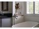 Bright bathroom featuring a soaking tub, stainless steel fixtures, and white shuttered window at 1610 Brock Ct, Las Vegas, NV 89117