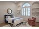 Bright bedroom featuring a vaulted ceiling, arched window, chair, and built-in shelving at 1610 Brock Ct, Las Vegas, NV 89117