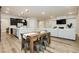 Open-concept dining area with a wooden table and chairs, flowing seamlessly into the living room and modern kitchen at 2450 Amatrice St, Henderson, NV 89044