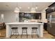 Modern kitchen featuring black cabinets, stainless steel appliances, and a large white center island at 2450 Amatrice St, Henderson, NV 89044