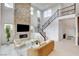 Bright living room featuring a stone fireplace, high ceilings, and a staircase with decorative iron railings at 350 Gandara St, Las Vegas, NV 89138