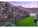 Modern backyard features a small grass area, fireplace, and perimeter fencing at 358 Solitude Peak Ln, Henderson, NV 89012
