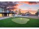 Beautiful backyard featuring a putting green, patio, and lush landscaping at sunset at 4061 W Eldorado Ln, Las Vegas, NV 89139