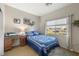 Comfortable bedroom with a blue quilt, wood desk, and natural light from the large window at 4937 Semifonte Dr, Pahrump, NV 89061