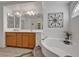 Bright bathroom featuring dual sinks, a soaking tub with tile surround, and a large mirror at 5080 Plymouth Bay Ct, Las Vegas, NV 89141