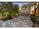 Two-story home with neutral paint, balcony, brick driveway and mature trees at dusk at 5080 Plymouth Bay Ct, Las Vegas, NV 89141