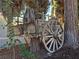 A wooden wagon decor piece, with large wheels and a harness, adding rustic charm to the outdoor landscape under mature trees at 5159 N Monte Cristo Way, Las Vegas, NV 89149