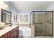 Well-lit bathroom featuring a soaking tub, glass enclosed shower and vanity with wood cabinets at 5441 Rose Hills St, Las Vegas, NV 89149