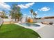 Refreshing pool area featuring a small building, lush green turf, desert trees, and a cozy fire pit at 5937 Round Castle St, Las Vegas, NV 89130