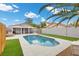 The image showcases a swimming pool with a covered patio and green turf in the backyard at 5937 Round Castle St, Las Vegas, NV 89130