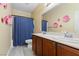 Bathroom featuring a double sink vanity, flower decor, and a shower with a blue curtain, creating a functional space at 6049 Paddleboat St, North Las Vegas, NV 89031