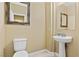 Neutral powder room with a pedestal sink, a framed mirror, and a toilet, offering a simple and functional design at 6049 Paddleboat St, North Las Vegas, NV 89031
