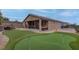 Sprawling backyard featuring artificial turf, a putting green, built-in seating, and a covered patio at 6985 Hopi Summit Ct, Las Vegas, NV 89149