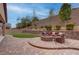Lush backyard features a fire pit seating area, artificial turf, and mature trees for privacy at 6985 Hopi Summit Ct, Las Vegas, NV 89149