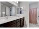 Well-lit bathroom featuring double sinks, dark cabinets, and a separate shower area at 6985 Hopi Summit Ct, Las Vegas, NV 89149