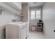 Well-lit laundry room with white washer and dryer, built-in shelves, and a window at 6985 Hopi Summit Ct, Las Vegas, NV 89149