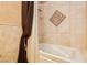Clean white tub and shower combo featuring tan ceramic tile and bronze fixtures at 7625 Coley Ave, Las Vegas, NV 89117