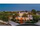 Expansive estate at twilight with illuminated windows, manicured greenery, and majestic palm trees dotting the landscape at 7625 Coley Ave, Las Vegas, NV 89117