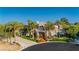 Elegant two-story house featuring a tile roof, lush landscaping, and a circular driveway with mature palm trees at 7625 Coley Ave, Las Vegas, NV 89117
