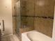 Bathroom featuring a glass shower, tub, and tiled walls with decorative mosaic tile at 7912 Foxwood Pl # 104, Las Vegas, NV 89145