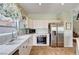 Bright kitchen featuring stainless steel appliances, white cabinets, and tile countertops with a floral valance at 7920 Aviano Pines Ave, Las Vegas, NV 89129