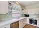 Cozy kitchen with white cabinets, stainless steel appliances, and tile countertops; featuring maple leaf accents at 7920 Aviano Pines Ave, Las Vegas, NV 89129