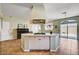 Open-concept kitchen with island cooktop, tile flooring, access to the patio, and plenty of natural light at 7920 Aviano Pines Ave, Las Vegas, NV 89129