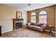 Comfortable living room with a tufted sofa, stone fireplace, and arched windows at 7920 Aviano Pines Ave, Las Vegas, NV 89129