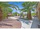 Lush backyard garden with mature palms, stone pathway, and shaded seating area at 7986 Merlewood Ave, Las Vegas, NV 89117