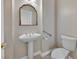 Compact half-bathroom with pedestal sink, decorative mirror, and convenient toilet placement at 7986 Merlewood Ave, Las Vegas, NV 89117
