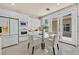 Bright dining area features a glass table, white chairs, and sliding glass doors, adjacent to the kitchen at 7986 Merlewood Ave, Las Vegas, NV 89117