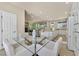 Glass dining table and white chairs between kitchen and living room at 7986 Merlewood Ave, Las Vegas, NV 89117