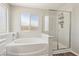 Bright bathroom featuring a bathtub, a glass-enclosed shower, and a large window at 914 Appaloosa Hills Ave, North Las Vegas, NV 89081