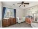 Bright bedroom with a crib, dresser, bookcase, and a comfortable chair for a soothing aesthetic at 914 Appaloosa Hills Ave, North Las Vegas, NV 89081