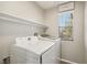 Convenient laundry room with modern washer and dryer, shelving, and a window for natural light at 914 Appaloosa Hills Ave, North Las Vegas, NV 89081
