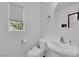 Bright, minimalist bathroom with a white sink, toilet, and a view from the window at 9141 Careful Canvas Ave, Las Vegas, NV 89149
