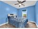 Bright bedroom featuring a ceiling fan, window view, wood-style flooring and a blue-painted wall at 9141 Careful Canvas Ave, Las Vegas, NV 89149