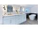Stylish bathroom boasts double sinks, marble counters, gold fixtures, a soaking tub and a large arched window at 9541 Summersweet Ct, Las Vegas, NV 89123