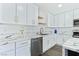 Kitchen area showcasing the stainless steel dishwasher, white cabinets, and marble countertops at 9541 Summersweet Ct, Las Vegas, NV 89123