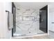 Modern walk-in shower features marble tile, glass enclosure, and sleek black accents, blending style and functionality at 9541 Summersweet Ct, Las Vegas, NV 89123